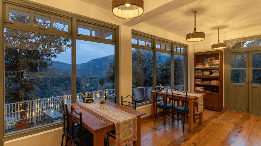 An indoor dining area with wooden tables and large windows at Ziran Retreat.