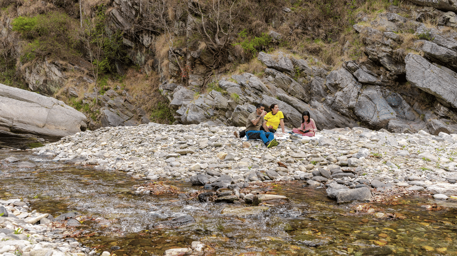A person sitting on a rock in the middle of a shallow river near Ziran Retreat.