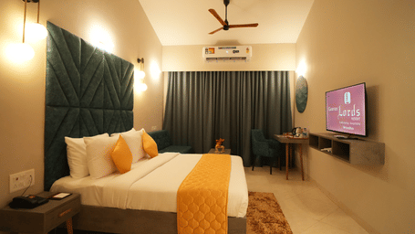A double bed with ceiling fan, TV, windows with curtains and AC