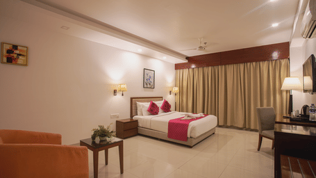 Comfortable hotel room at Diamond Palace Lords Plaza with a double bed, seating area, work desk, and a large window.