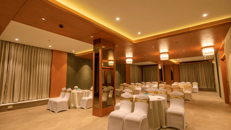 A softly lit function room at Lords Eco Inn Apple Gate is arranged with round tables and covered chairs, ready for an event.