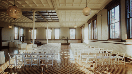A wedding hall with rows of chairs facing a decorated altar, set under warm lighting with elegant floral arrangements