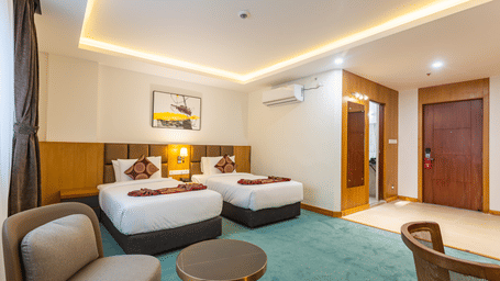 A twin bed room with attached bathroom, seating area and bedside lamp in our hotel rooms in Kathmandu.