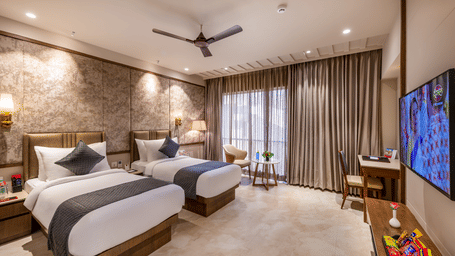 Full view of the Executive Room featuring twin beds facing towards the wall-mounted television above the TV cabinet - Skkylight Lords Inn, Nanded