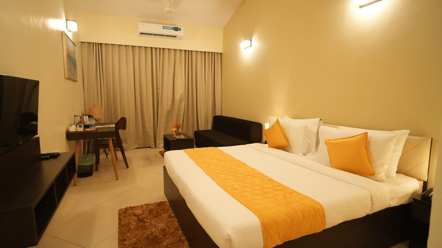 A dimly lit double bed room with windows, curtains, TV, AC and work desk