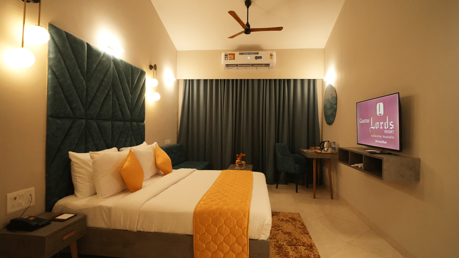 A double bed room with TV, lights and a work desk with chair