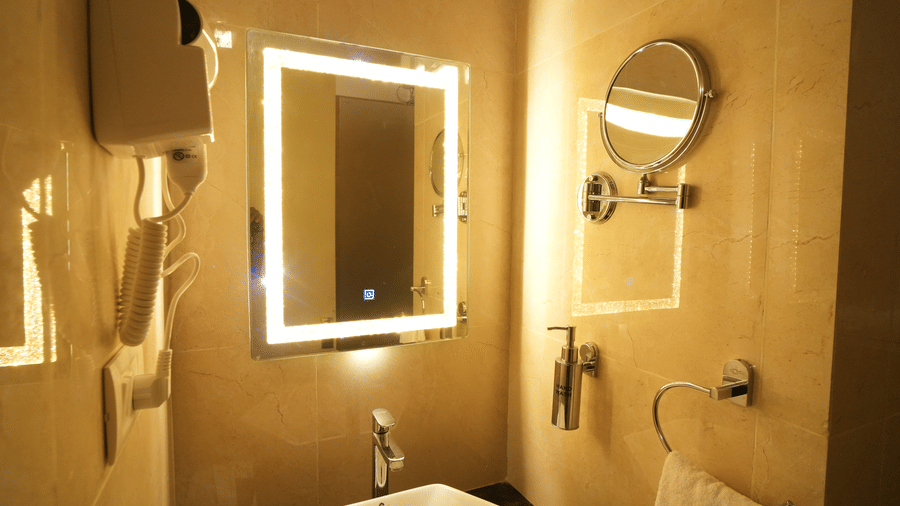 A side view of a sink area with hand towel and mirror with light