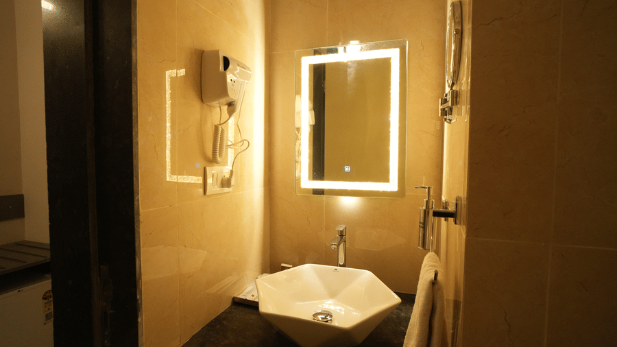 A sink area with hand towel and mirror with light