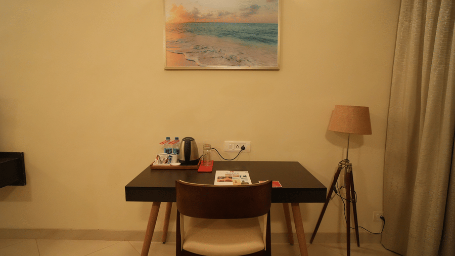 A work desk and chair with amenities, plug points, lamp and painting 