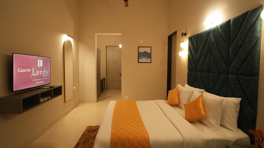 A side wide view of a double bed room with TV, AC and an hallway