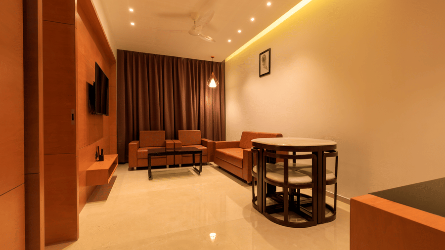 A warmly lit suite at Lords Eco Inn Apple Gate features orange sofas, armchairs, a coffee table, and a small dining set.