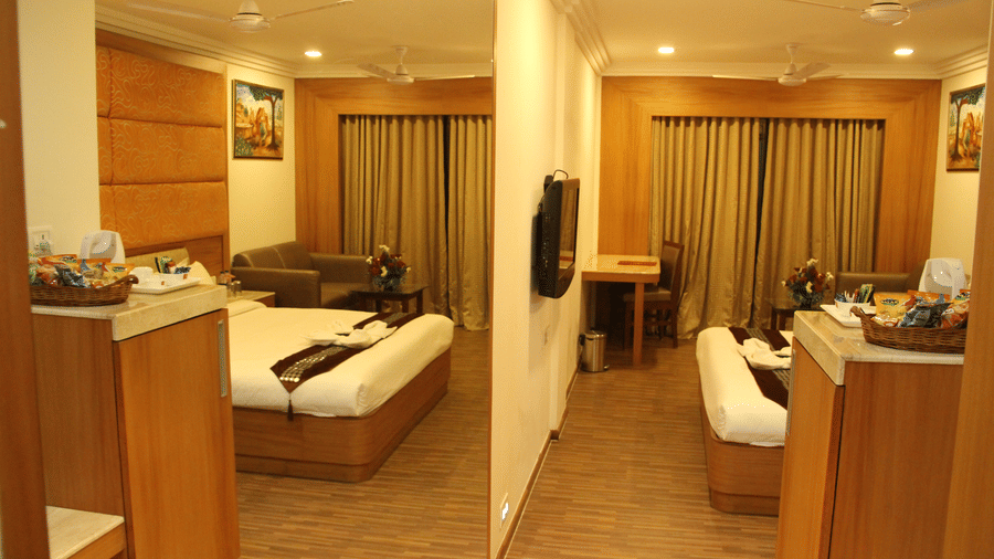 Spacious hotel room with sitting area and double bed, warmly lit