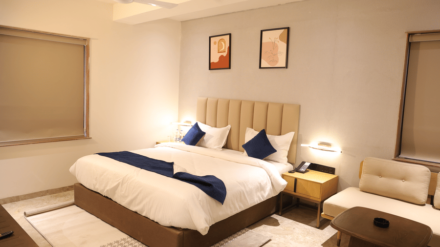 A luxurious Deluxe Room at Lords Studio Inn, Jamnagar showcasing a comfortable bed and contemporary furnishings.