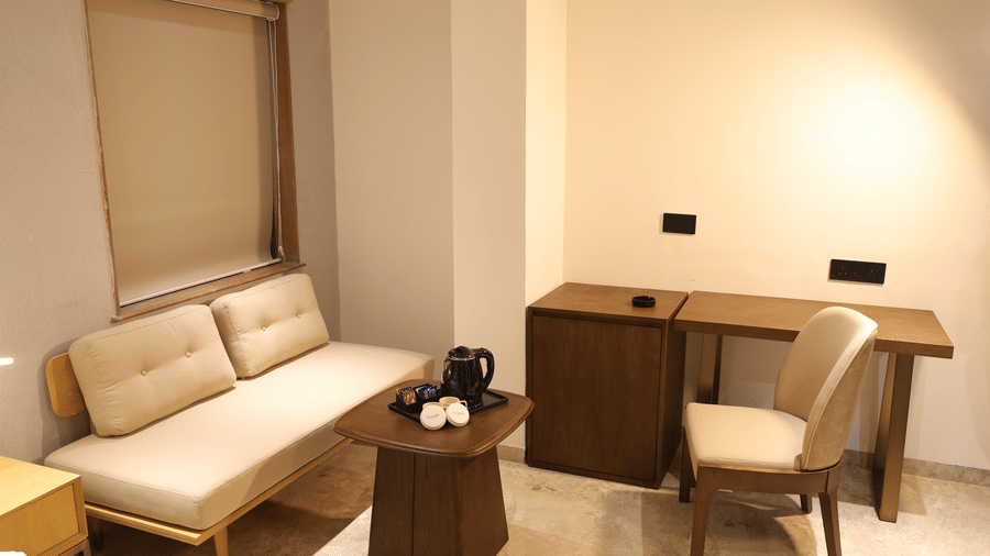 A well lit Deluxe Room at Lords Studio Inn, Jamnagar  featuring a sofa bed writing desk and coffee table