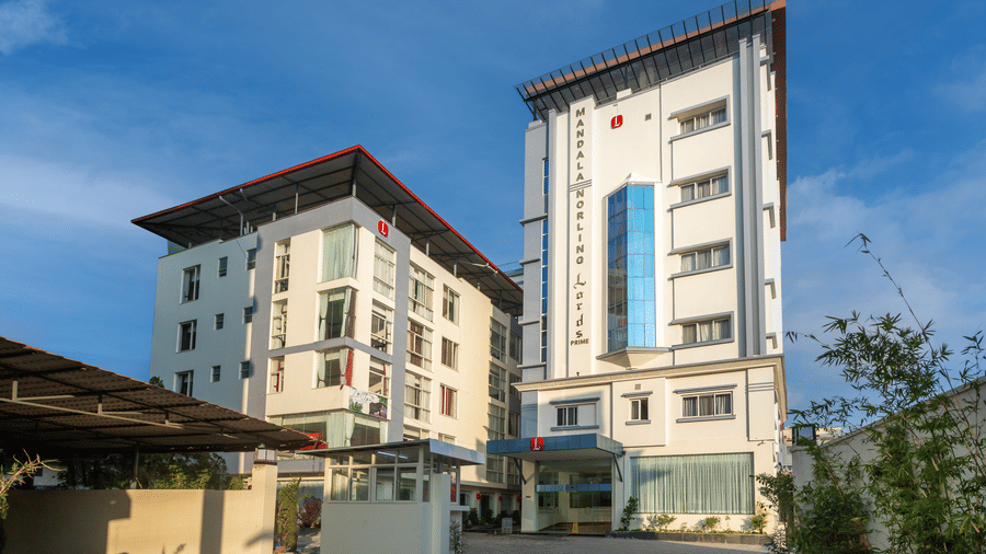 A multi-storey, modern building with a few cars parked in front.
