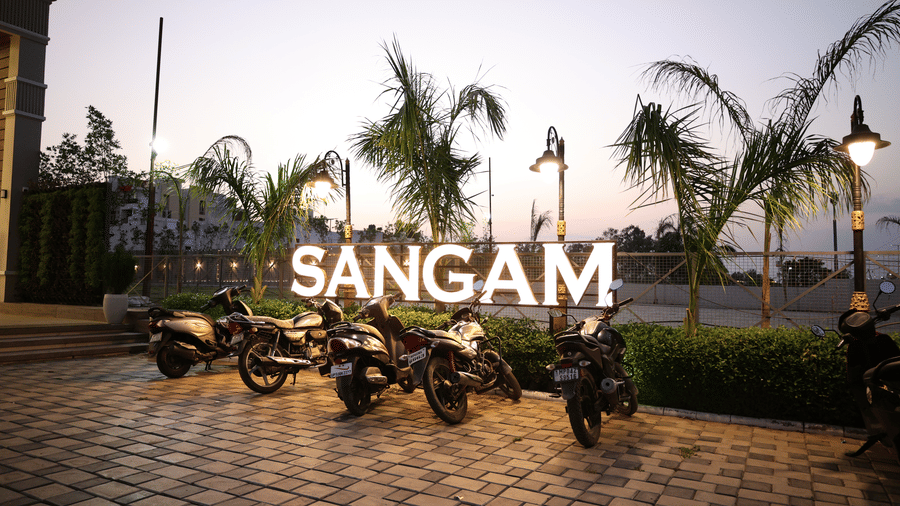 Motorbikes are parked outside the illuminated entrance sign at dusk - Lords Inn Sangam, Bhopal
