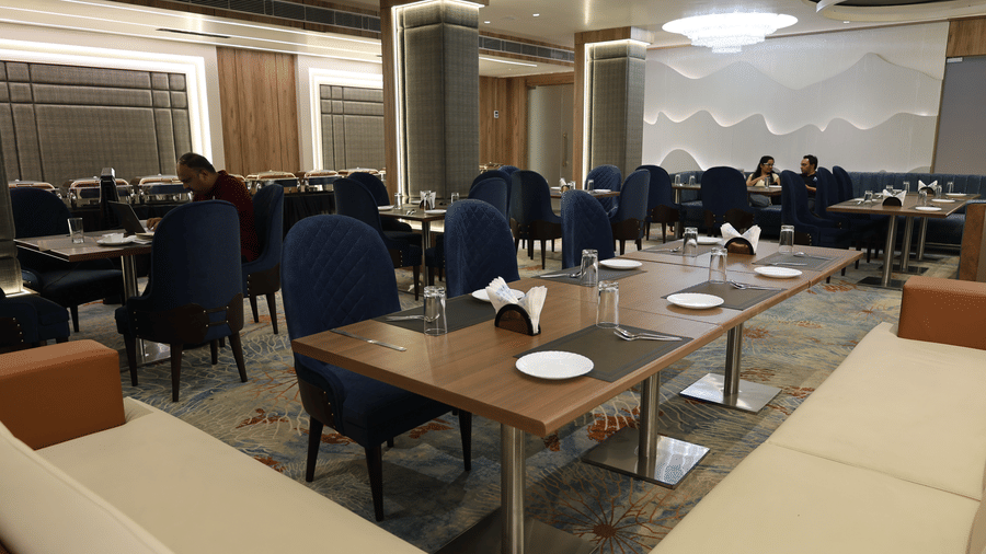 The spacious hotel restaurant features long tables and elegant contemporary seating - Lords Inn Sangam, Bhopal
