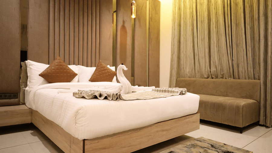 A double bed with brown cushions sits next to a small sofa by the window - Lords Inn Sangam, Bhopal