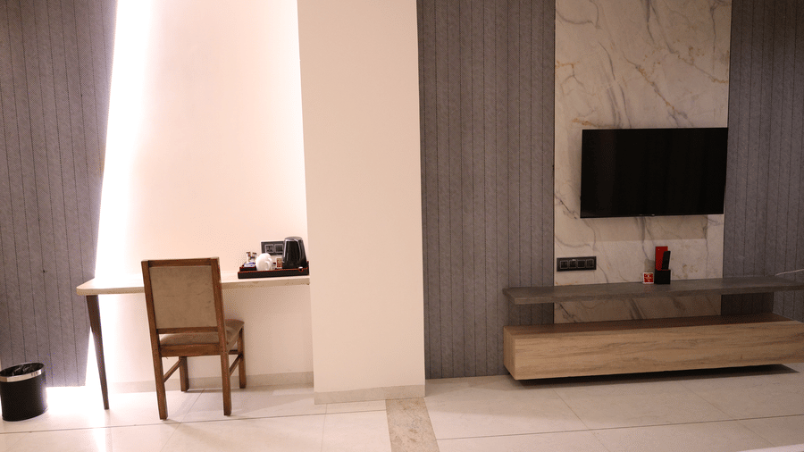 A study desk stands near a wall-mounted television in a bright hotel room - Lords Inn Sangam, Bhopal