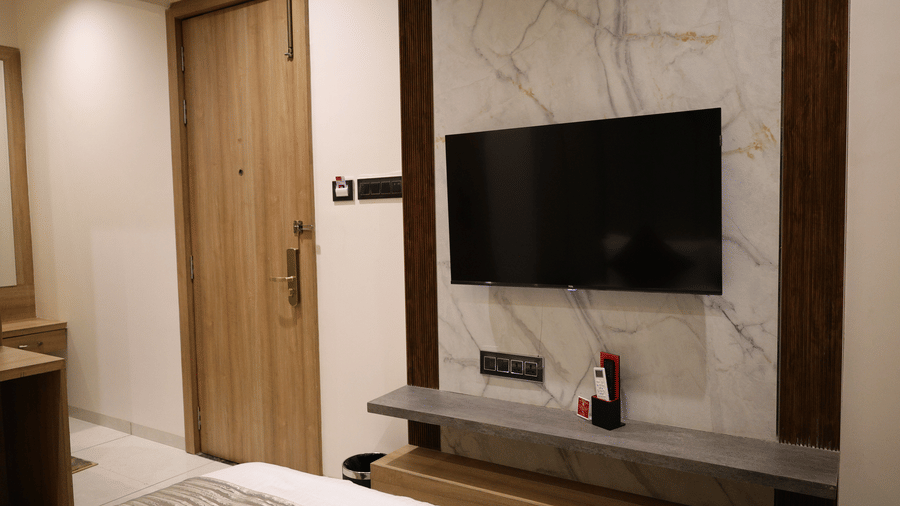A sleek television is mounted onto a modern marble-style wall panel - Lords Inn Sangam, Bhopal