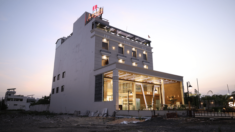 The side view of the modern multi-storey hotel building stands tall against a twilight sky - Lords Inn Sangam, Bhopal