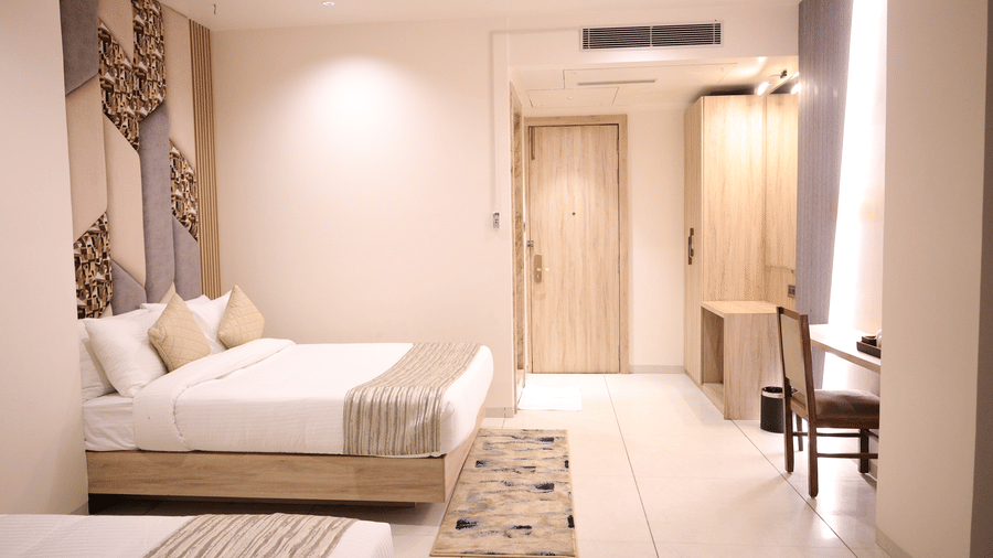 A bright hotel bedroom includes a comfortable bed and a wooden desk setup - Lords Inn Sangam, Bhopal