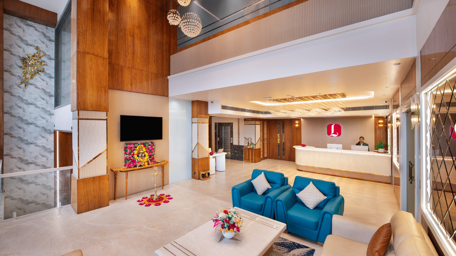 Cosy lobby seating area at Lords Inn Sangam, Bhopal with a teal sofa, wooden coffee table, floral decor, and warm wood-paneled walls.