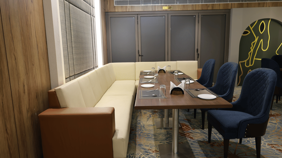 A long dining table is paired with a white sofa bench and blue armchairs - Lords Inn Sangam, Bhopal