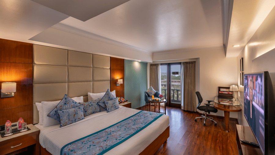 Elegant Club Room featuring a king-size bed and a sitting area near a window at Lords Plaza Jaipur.