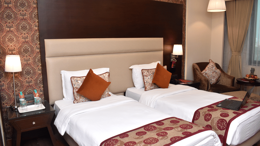 A hotel room with twin beds and comfortable seating at Lords Plaza Surat showcasing their modern interiors