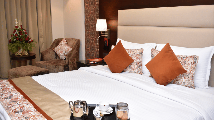 A comfortable double bed with pillows and a decorative throw in a room at Lords Plaza Surat, highlighting the hotel's modern interiors.