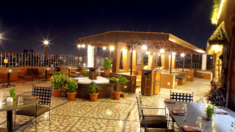 A modern, illuminated rooftop dining area of Lords Plaza at night with comfortable seating