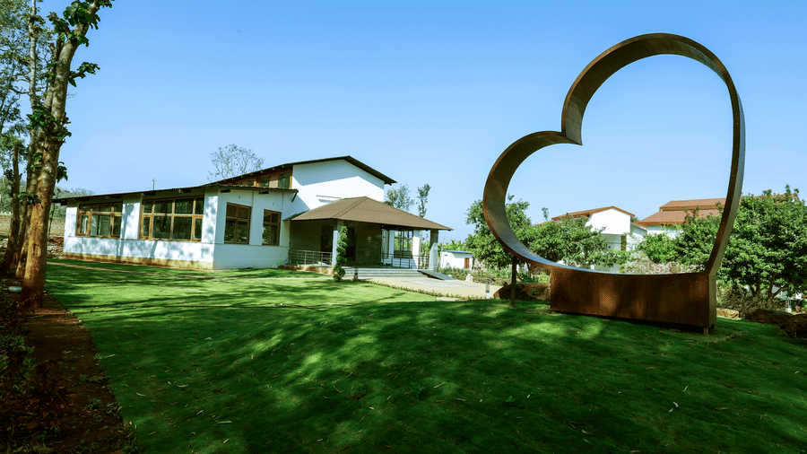 A manicured green lawn featuring a large heart-shaped metal structure with a resort building in the background | Lords Sahyadri Resort, Shivamogga
