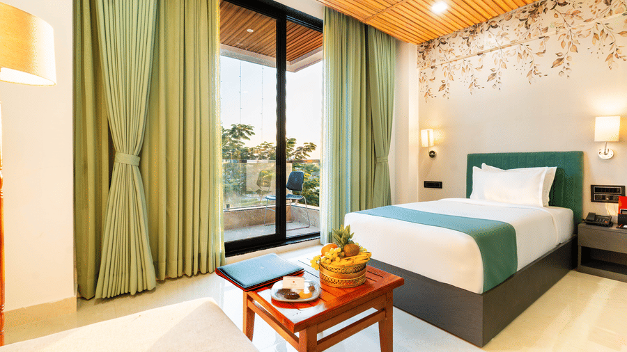 Elegant guest room at Lords SKD Resort, Salangpur, with a wooden-slat ceiling, balcony access, and fresh fruit on a coffee table.