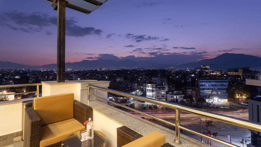 View of the urban and hilly landscape under purple and pink sky from an outdoor seating area at the best hotel in Kathmandu, Nepal, Mandala Norling Lords Prime.
