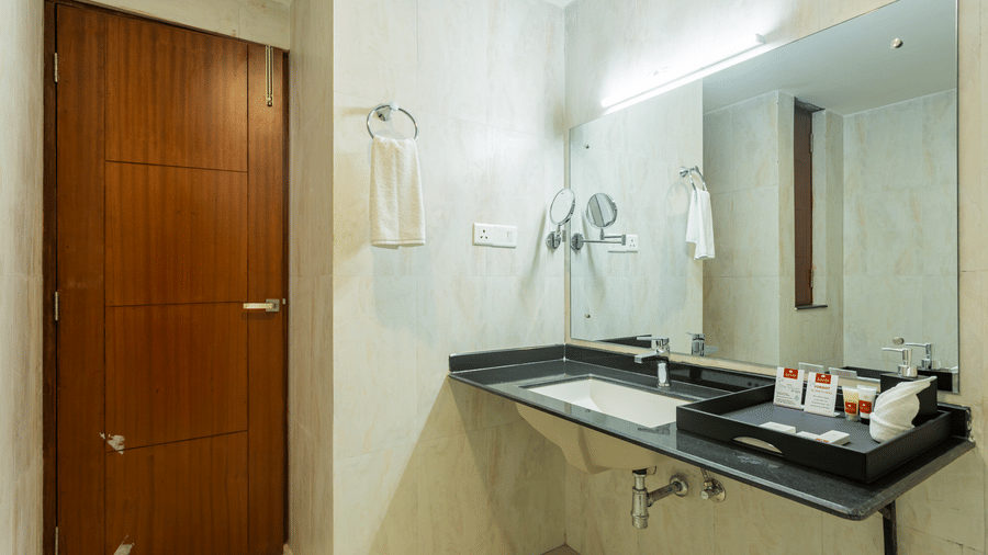 A bathroom sink area with hand towel, mirror and toiletries