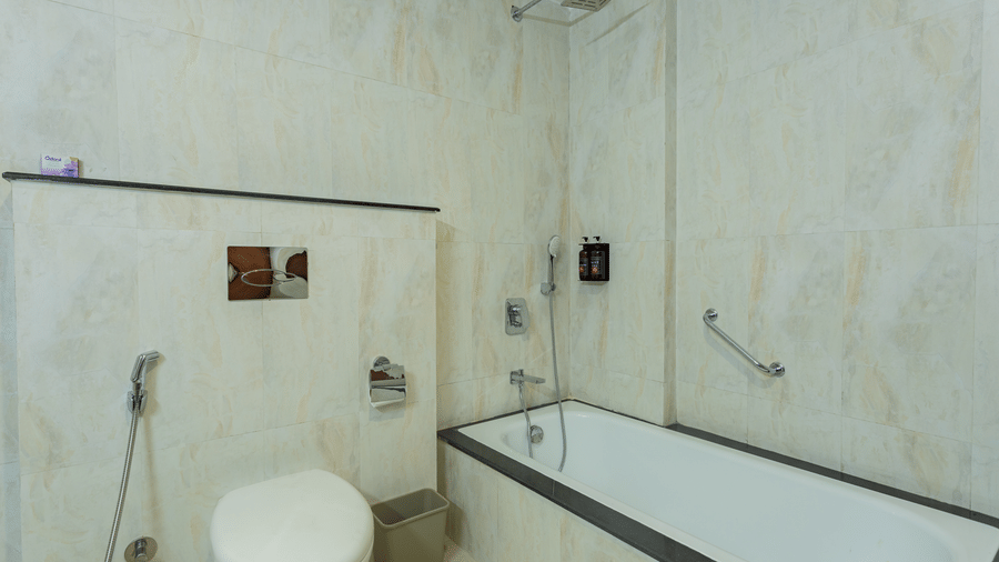 Bathtub with hand-shower, amenities and a toilet