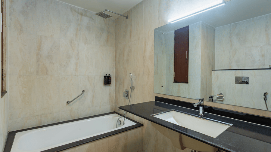 A bath tub with sink and mirror on the side