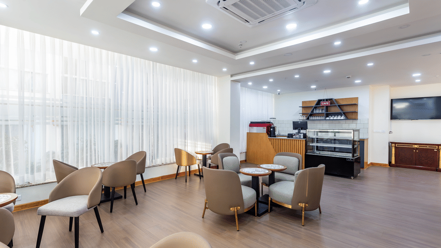 Spacious interior of L Cafe at Mandala Norling Lords Prime Kathmandu with a service bar, television, and contemporary furniture.