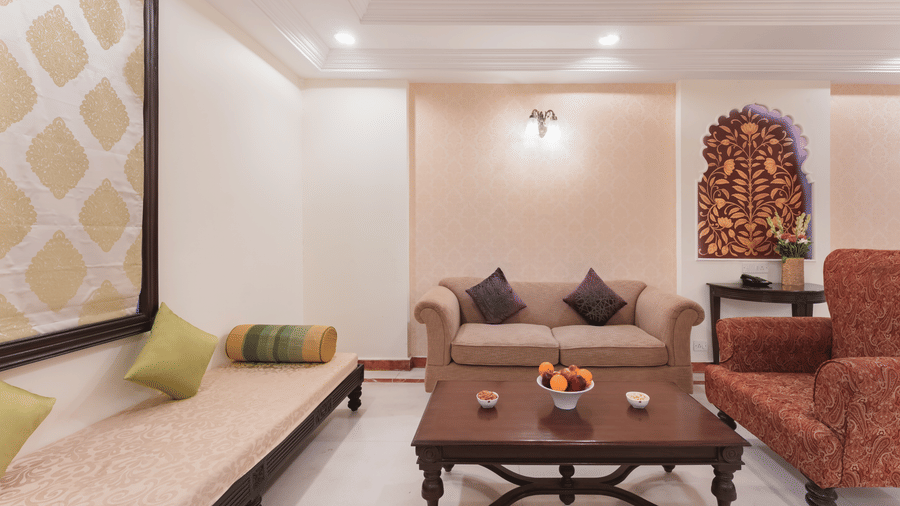 A view of a living area at Shri Vallabh Vilas Lords Plaza Nathdwara, featuring traditional inspired furnishings, wall arts and pendant lights.