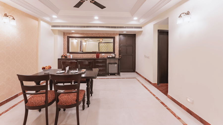 A view of a spacious dining area at Shri Vallabh Vilas Lords Plaza Nathdwara, with arranged seating table set featuring a mirror at the background.