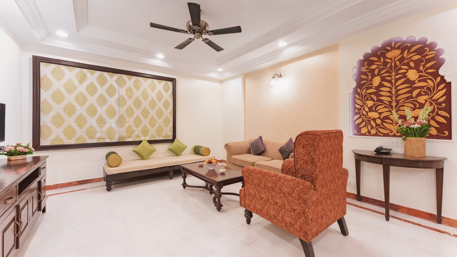 A spacious living area with traditional furnishings, creative wall arts and a ceiling fan at Shri Vallabh Vilas Lords Plaza Nathdwara.
