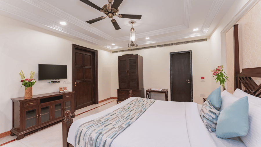 A premier suite at Shri Vallabh Vilas Lords Plaza Nathdwara, featuring twin size bed, pendant lights, wooden furnishings, wardrobe and a T.V.