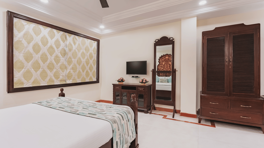 A club room at Shri Vallabh Vilas Lords Plaza Nathedwara, featuring a bed with a dining area, a wall mirror, pendant lights and a wardrobe and a T.V.