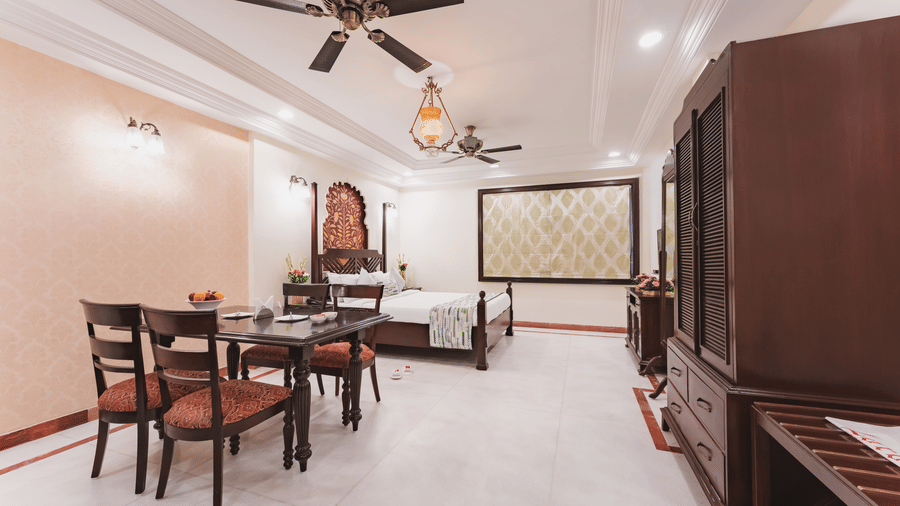 A bedroom with a dining space at Shri Vallabh Vilas Lords Plaza Nathdwara, featuring traditional architect furnishings, wall arts, pendant lights, and a wardrobe.