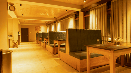 Rows of cushioned booths and wooden tables fill the warmly lit room of The Mountain Hut Bistro at Mount Bayul Shangri-La Resort, Lachung, Lachung.