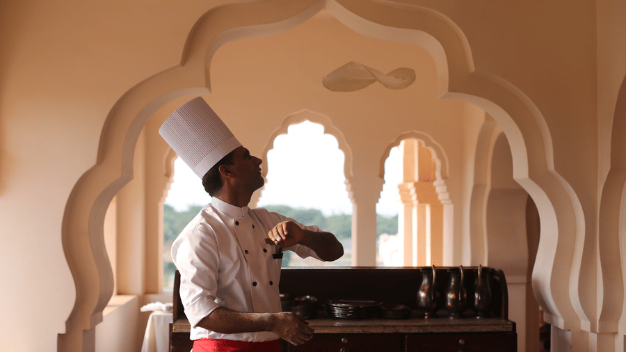 Chef or butler providing in-room service at an arched window at Evolve Back Hampi