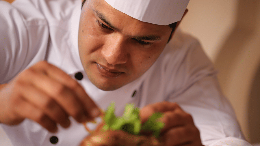 Chef carefully plating a gourmet dish at Evolve Back Hampi restaurant