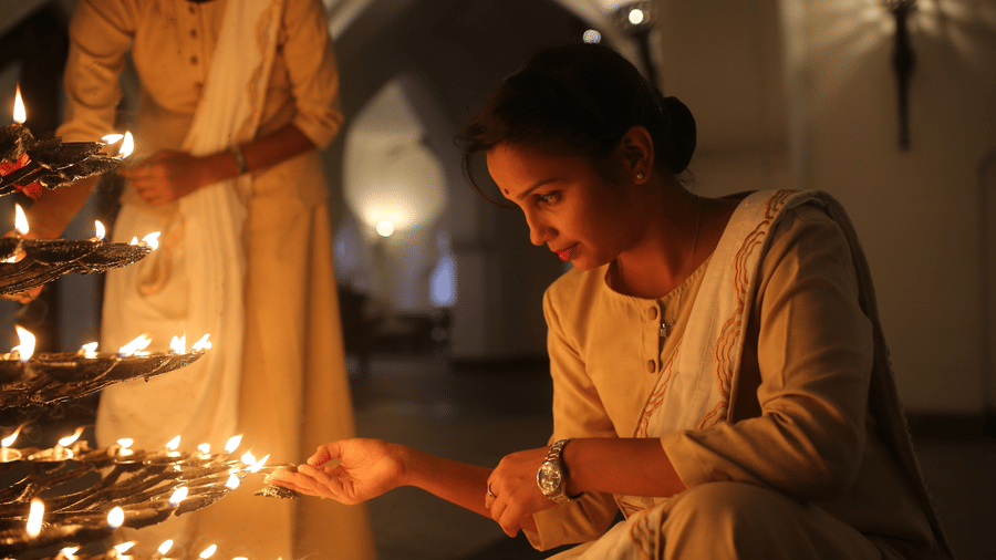 Woman lighting diyas in a spiritual ritual at Evolve Back Hampi