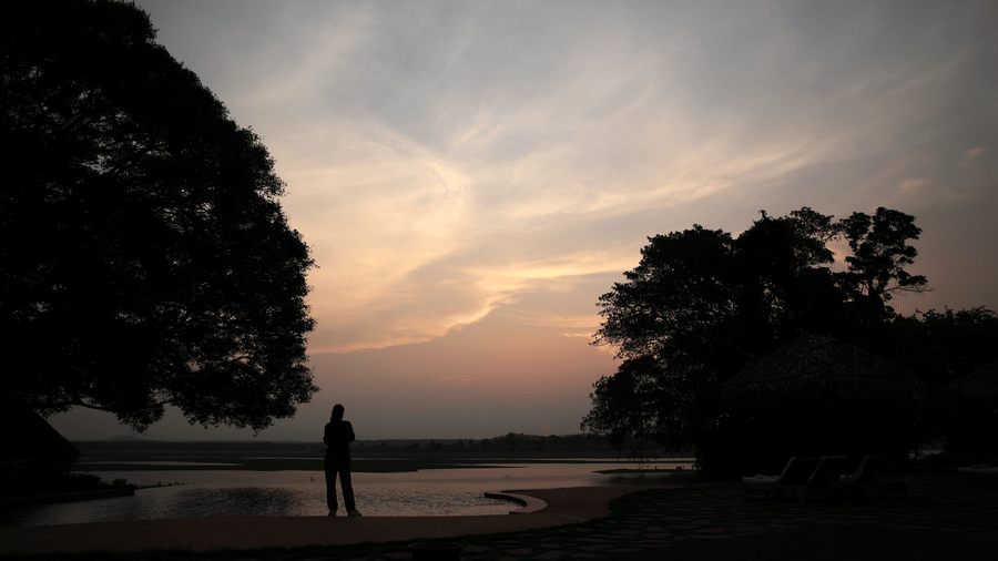 Silhouette of a guest watching sunset over the Kabini river near Evolve Back resort